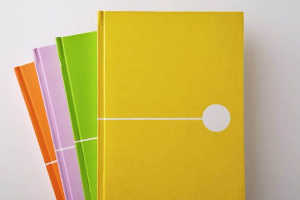 Tiga buku hardcover dengan warna cerah: oranye, ungu, dan hijau, diletakkan bersama.