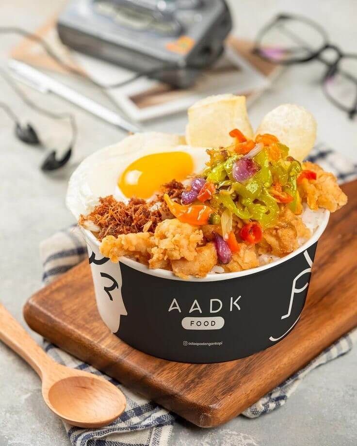 Makanan cepat saji Nasi Goreng AADK dengan telur rebus dan sayuran segar.