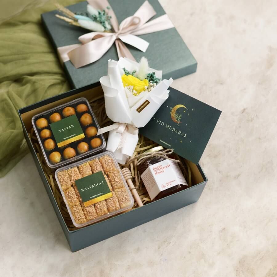 Paket hadiah lebaran dengan kue tradisional, madu, dan bunga mawar dalam kotak hijau.