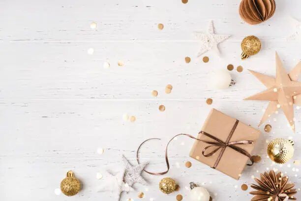 Tema Natal minimalis dengan kemasan hadiah, bintang, dan bola Natal emas di atas latar belakang kayu putih.