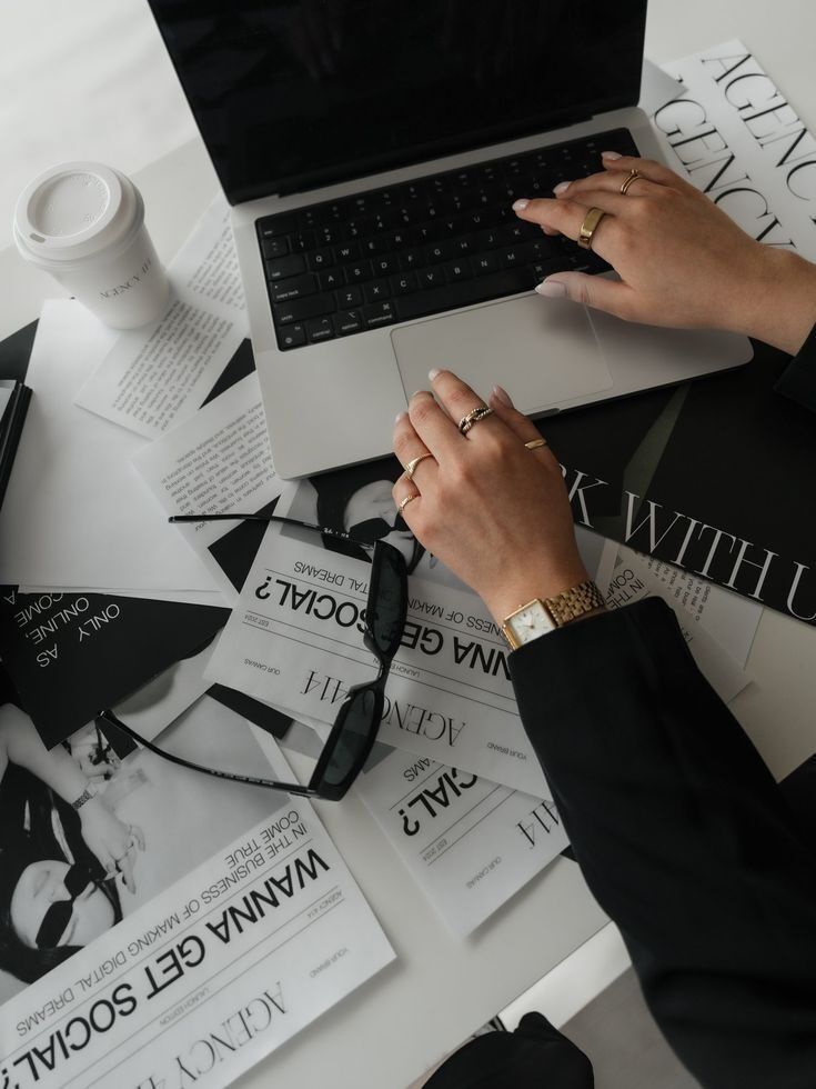 Tangan sedang mengetik di laptop di meja kerja dengan surat dan kopi
