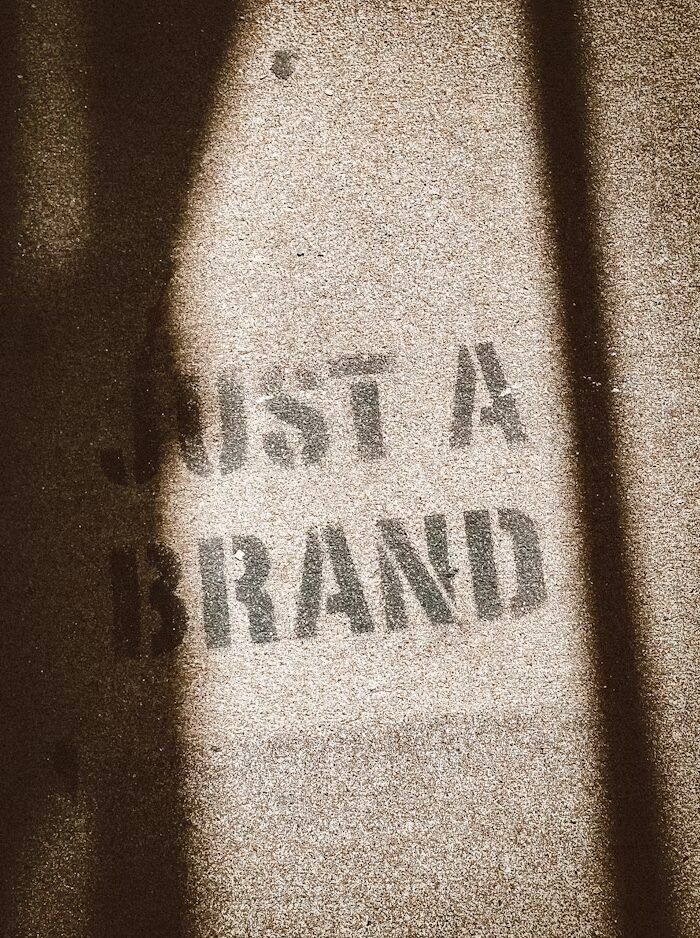 Gambar tulisan 'JUST A BRAND' yang terlihat seperti dicat pada permukaan beton.
