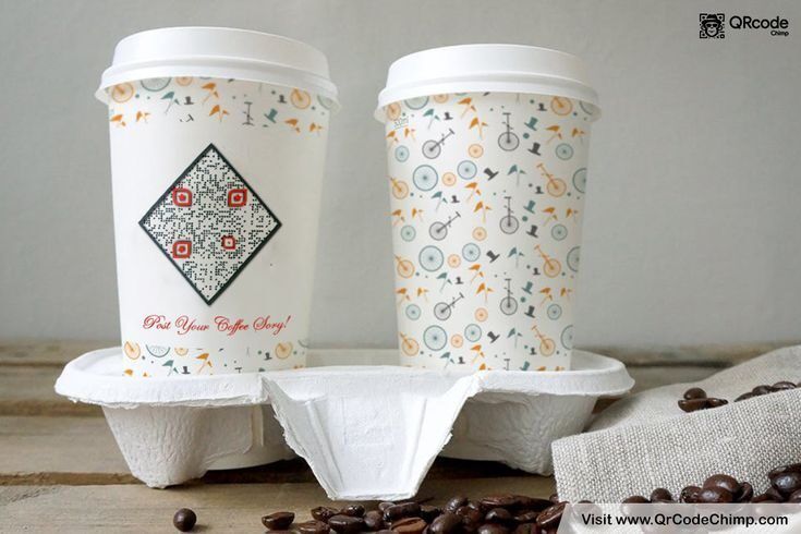 Dua cangkir kertas kopi dengan desain grafis dan QR Code, disajikan dengan biji kopi dan filter kopi.