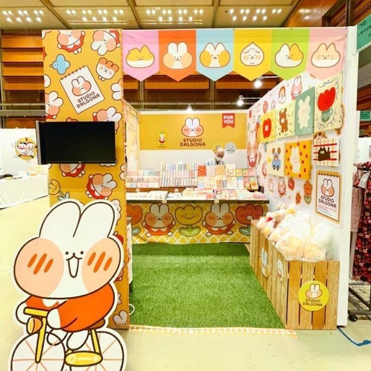 Stall percetakan online dengan desain karakter lucu dan berwarna-warni.