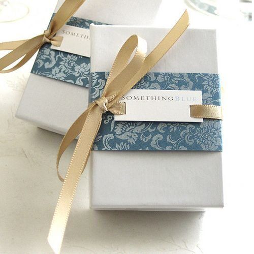 Kotak hadiah dengan kertas berdesain biru dan putih, dipotong dengan pita emas.