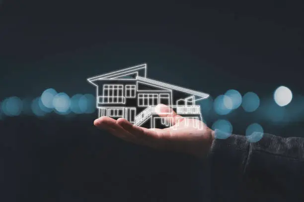 Tangan memegang model rumah 3D di malam hari