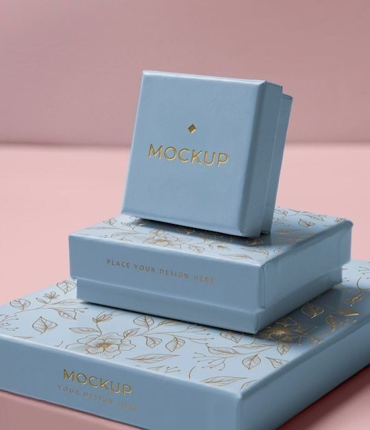 Mockup kotak perhiasan biru dengan desain floral dan tulisan 'MOCKUP' di depan.