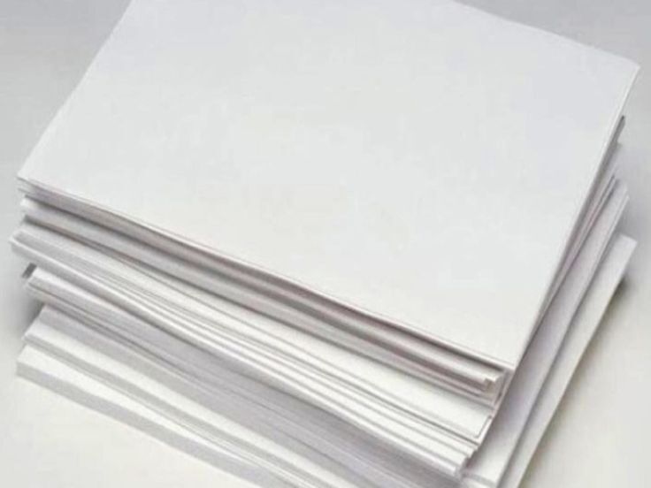 Pile of plain white paper sheets on a light background.