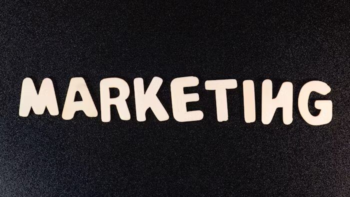Huruf-huruf besar 'MARKETING' berwarna putih di atas latar hitam.