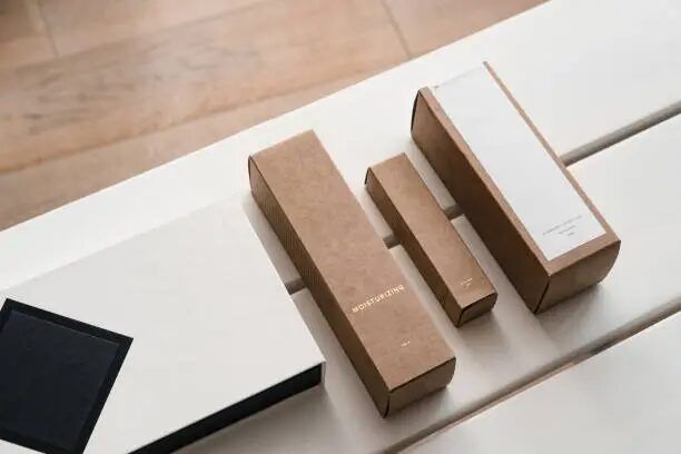 Kotak-kotak percetakan dari kertas kraft dengan desain minimalis di atas meja kayu.