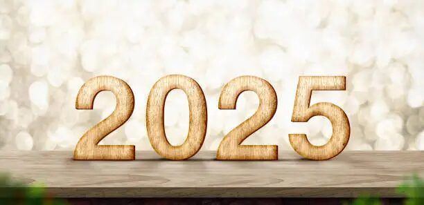 Huruf tahun 2025 berwarna coklat diletakkan di atas meja kayu.