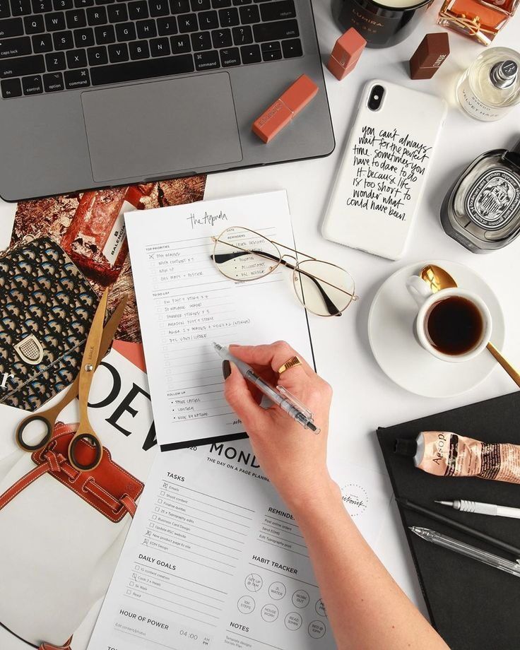 Tulis agenda harian dengan laptop dan alat kerja di meja kerja.