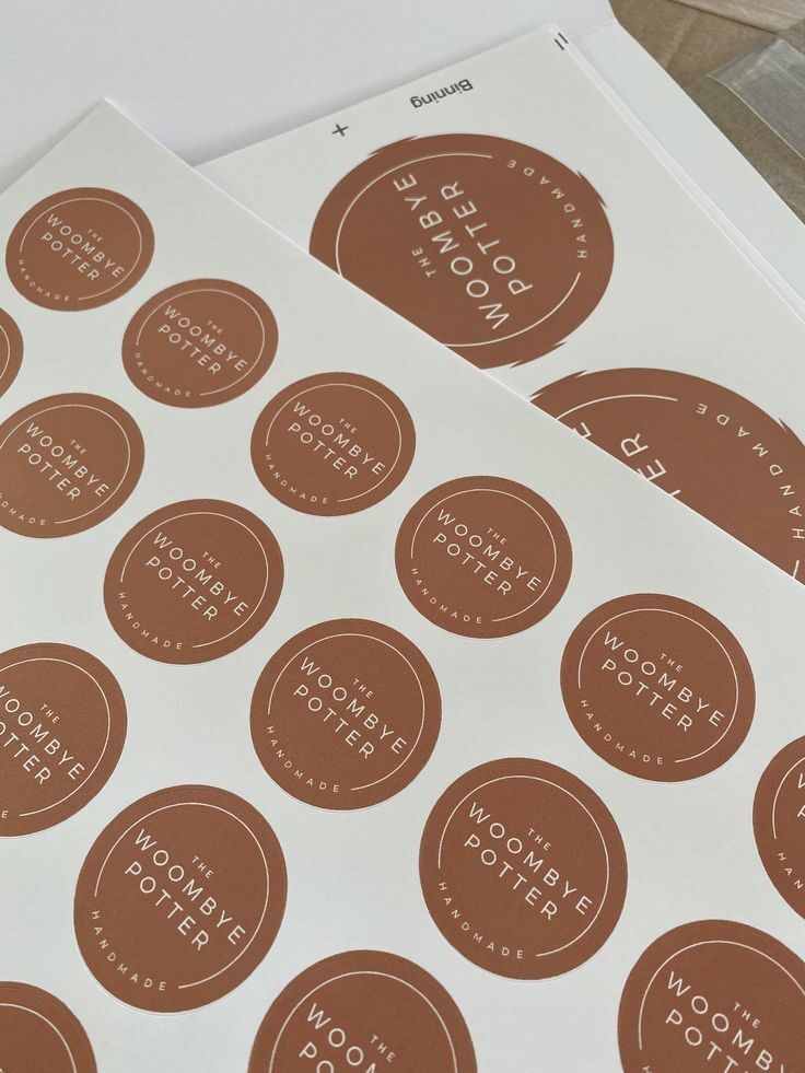 Stiker persegi dengan logo 'The Woombye Potter' dalam warna cokelat dan putih.