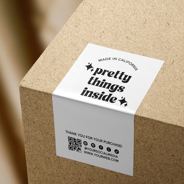 Stiker putih dengan pesan 'pretty things inside' dan 'made in California' di atas kotak karton.