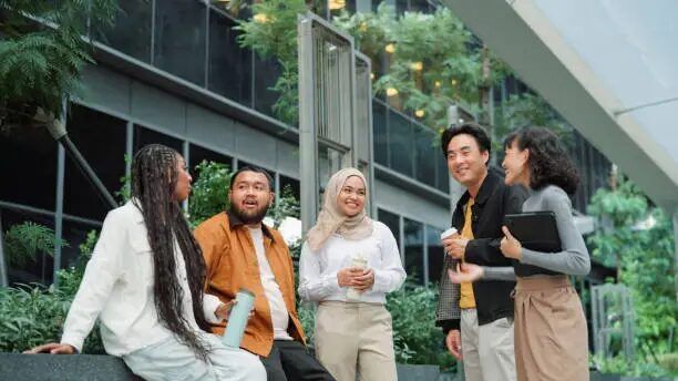 kelompok orang berbincang di depan bangunan perkantoran