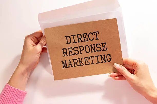 Tangan memegang kartu direct response marketing sebagai contoh media promosi cetak yang terukur