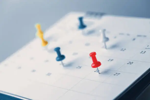 Kalender dengan pegangan warna merah, biru, dan kuning menandai tanggal-tanggal penting.