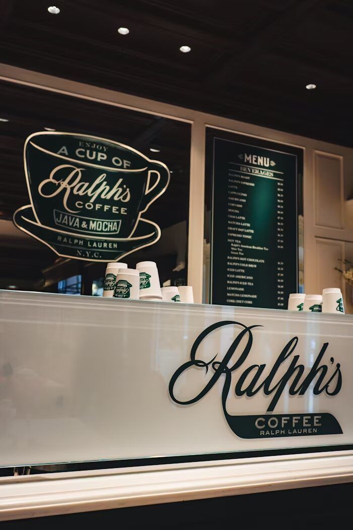 Toko kopi Ralph's dengan papan menu dan gelas kopi di meja.