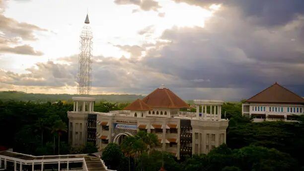 Pemandangan masjid modern dengan menara tinggi di tengah-tengah lingkungan hijau.
