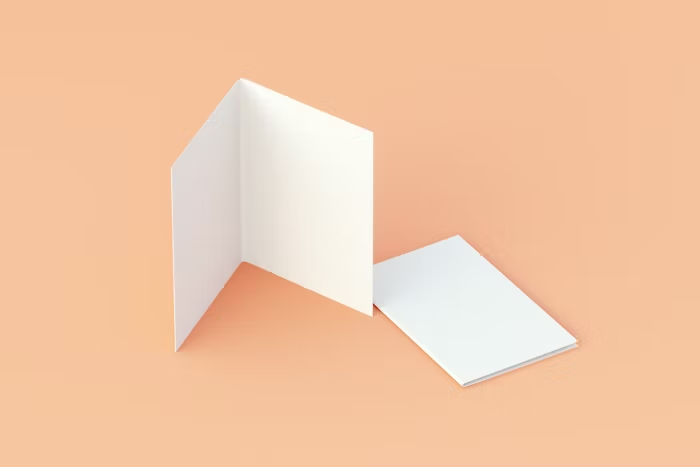 Buku lipat dan lembaran putih di latar warna pastel.