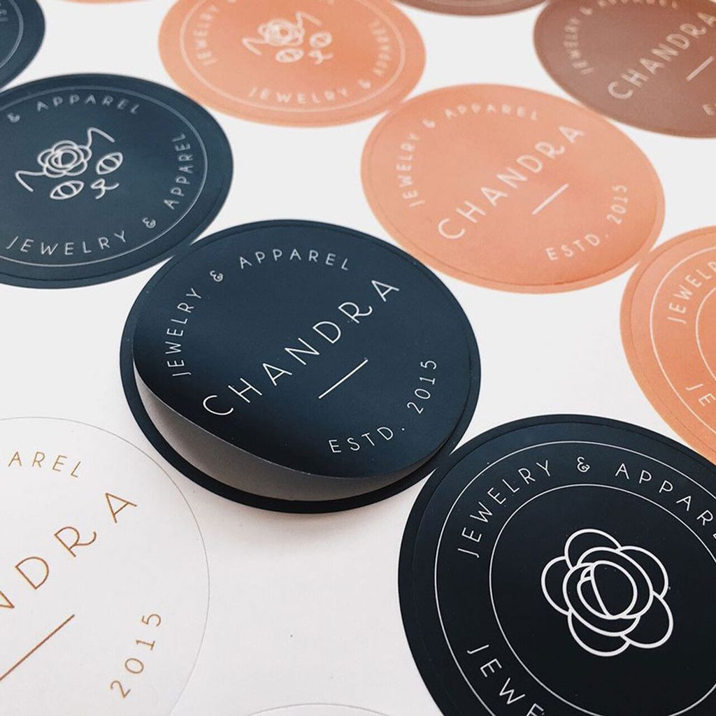Rangkaian label bulat dengan logo Chandra Jewelry & Apparel dalam warna hitam dan oranye.