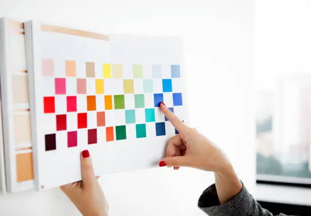 Tangan menunjuk pada warna biru dalam buku sampel warna