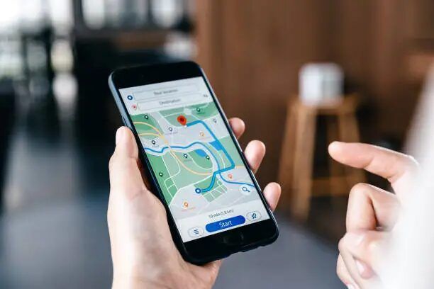 Tangan memegang smartphone dengan aplikasi GPS yang menunjukkan rute