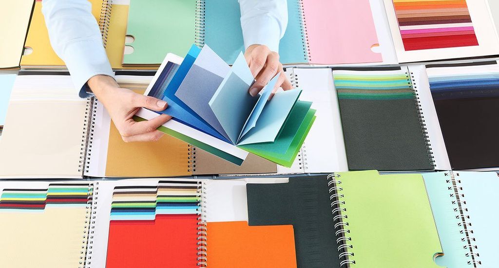 Tangan memilih warna dari buku sampel warna dalam percetakan online.