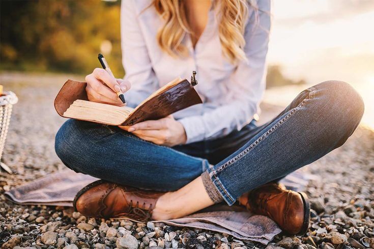 Orang menulis di buku dengan pena di latar alam