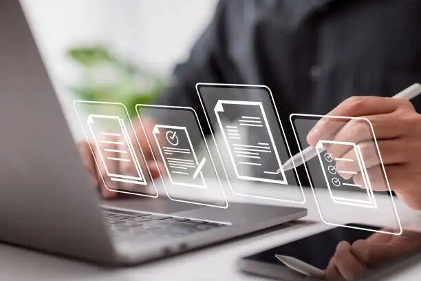 Tampilan layar laptop dengan tanda-tanda dokumen digital dan tangan menulis.