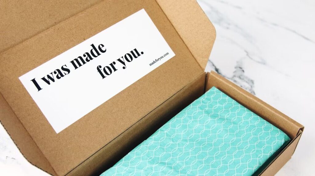 Kotak karton dengan pesan 'I was made for you' dan kain biru motif di dalamnya.
