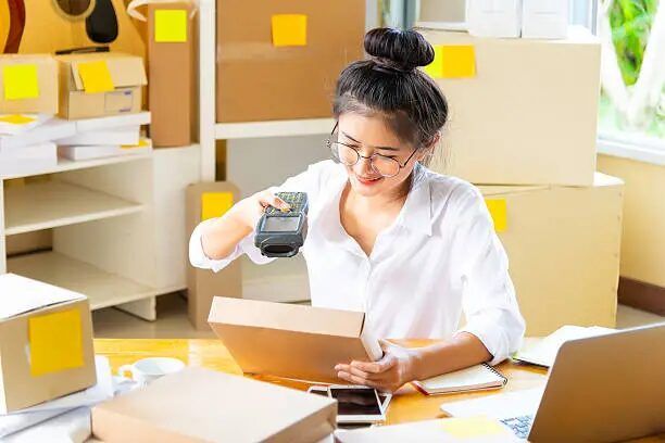 Perempuan sedang memindai barcode di kotak kemasan di kantor percetakan online.