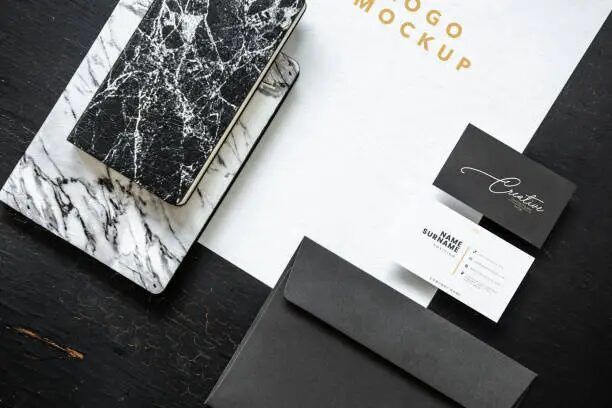 Rancangan branding dengan kertas, kartu nama, dan kantong surat.