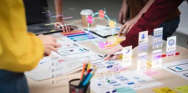 Tim desainer mengevaluasi prototipe aplikasi UI/UX di meja kerja.