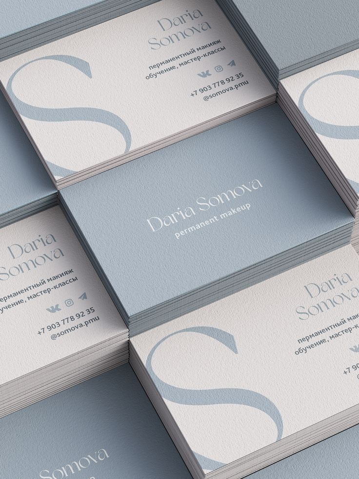 Kartu nama desain elegan dengan warna biru pastel dan logo besar.