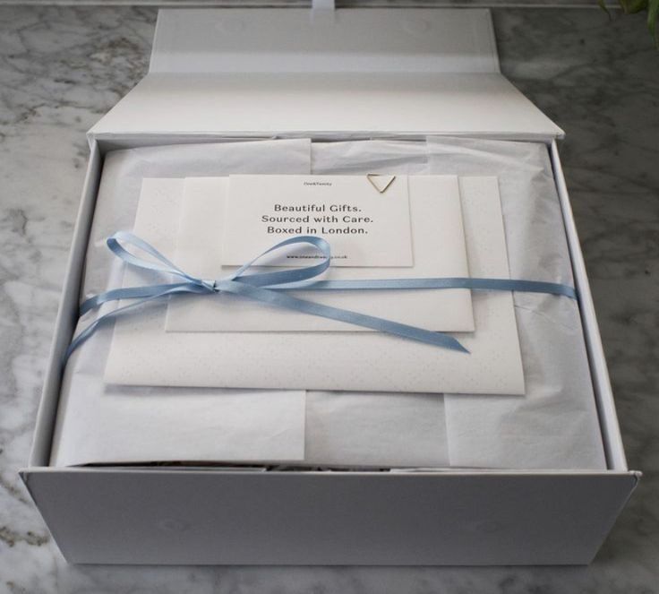 Paket hadiah elegan dengan kertas putih dan tali biru muda, diproduksi di London.