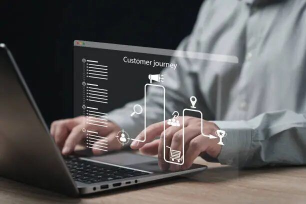 Tangan mengetik di laptop dengan layar hologram 'Customer Journey'