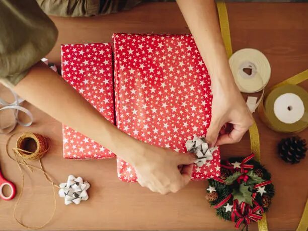 Tangan mempersiapkan hadiah Natal dengan kertas bintang merah dan hijau