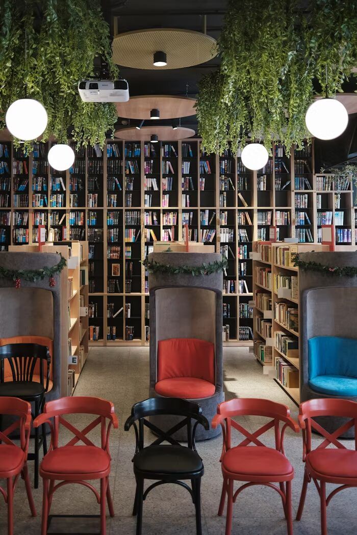 Interior perpustakaan modern dengan rak buku dan kursi merah.