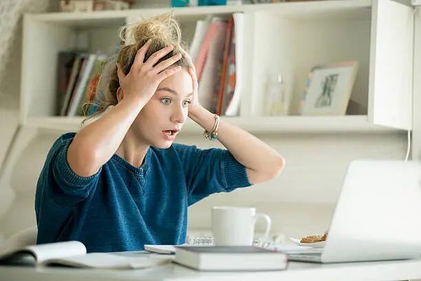 Perempuan sedang bekerja di depan laptop di ruang kerja.