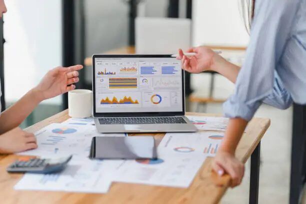 dua orang sedang membahas grafik di laptop dan dokumen