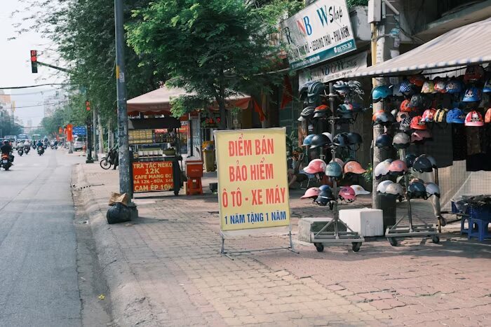 Penjual helm di pinggir jalan dengan spanduk iklan yang harus mudah terbaca dari lalu lintas.