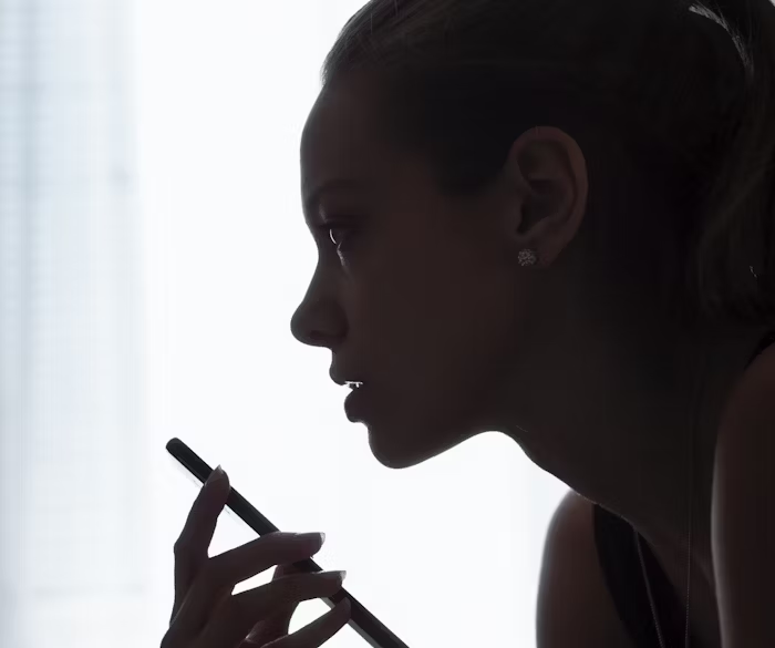 Wanita sedang menggunakan pensil di depan jendela, siluet halus.