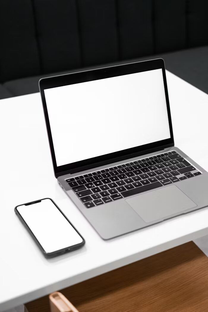 Laptop dan smartphone dengan layar putih di meja putih