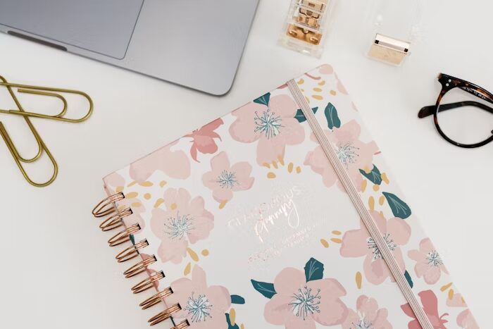 Notebook cantik dengan desain bunga mawar dan pola warna-warni, cocok untuk dekorasi meja kerja.