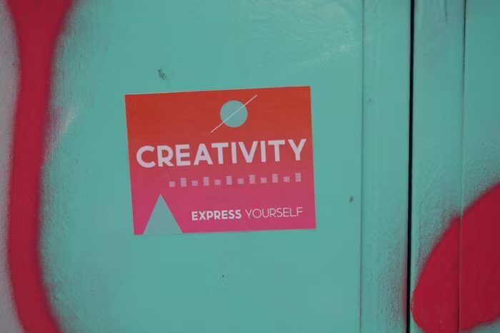 Stiker merah bertuliskan 'Creativity Express Yourself' di permukaan biru.
