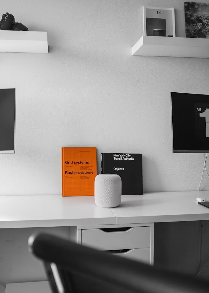 Meja kerja minimalis putih dengan speaker dan buku, suasana kerja modern