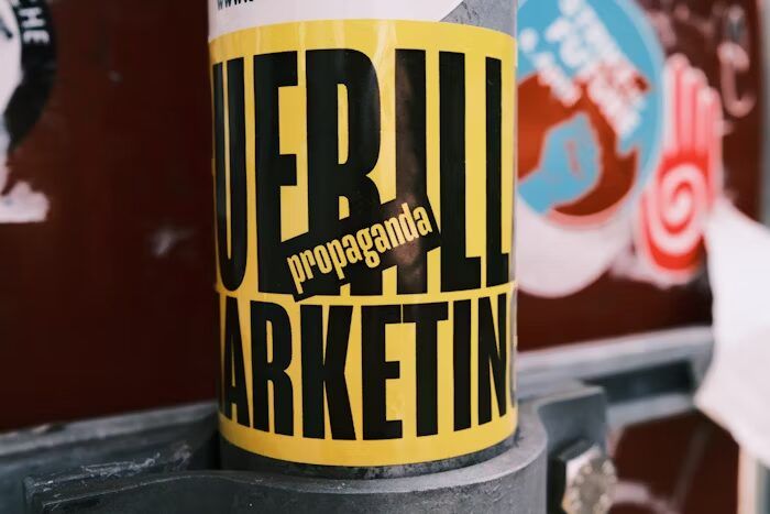 Stiker bertuliskan 'Guerrilla Marketing' dengan warna dan desain menarik.