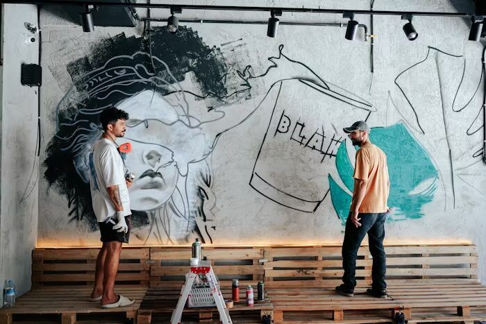 dua orang pekerja sedang memasang mural di dinding workshop.