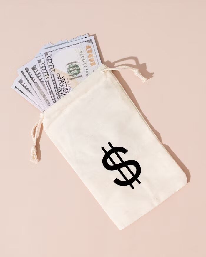 Dompet putih dengan simbol dolar dan uang kertas untuk menggambarkan estimasi biaya cetak booklet A5 landscape per pcs